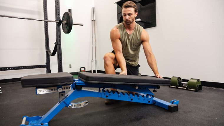 Breaking Muscle team member adjusts the REP Fitness BlackWing bench to a flat position.