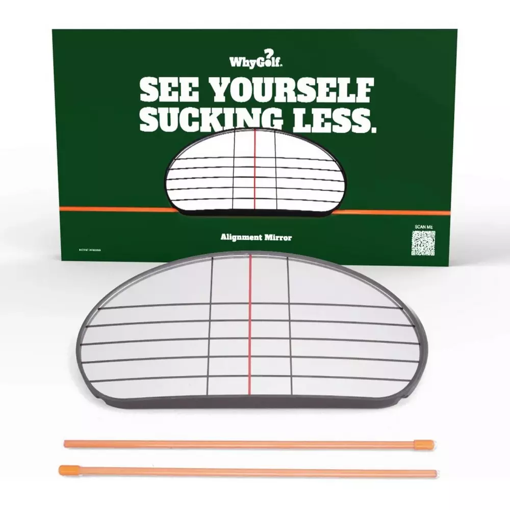 A golf alignment mirror with a grid pattern, designed as a training aid to improve your golf swing and set up, is placed in front of a green sign that reads SEE YOURSELF SUCKING LESS. Two orange rods are in front of the mirror.