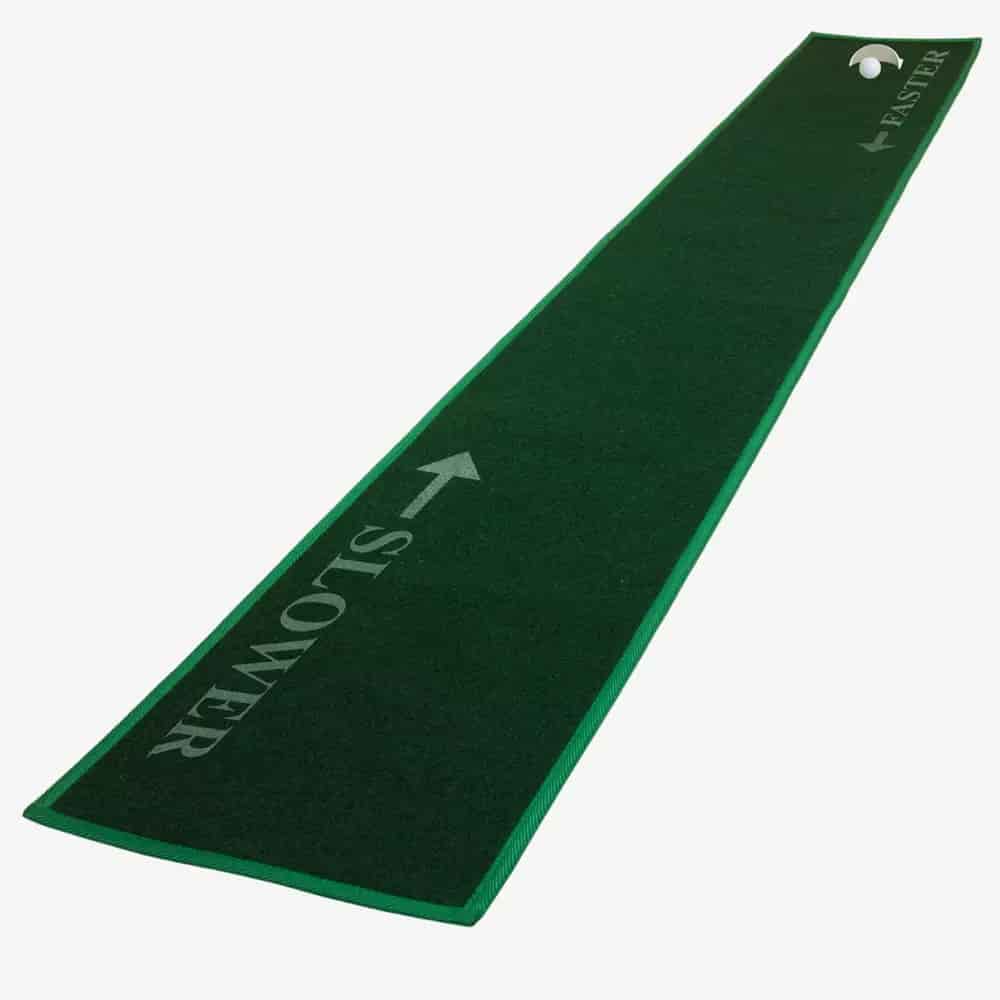 A long, narrow green putting mat with a golf hole at one end. The mat features arrows and the words SLOWER and FASTER for different speed zones&mdash;perfect for honing your skills before packing up your gear in the best golf bags 2026.
