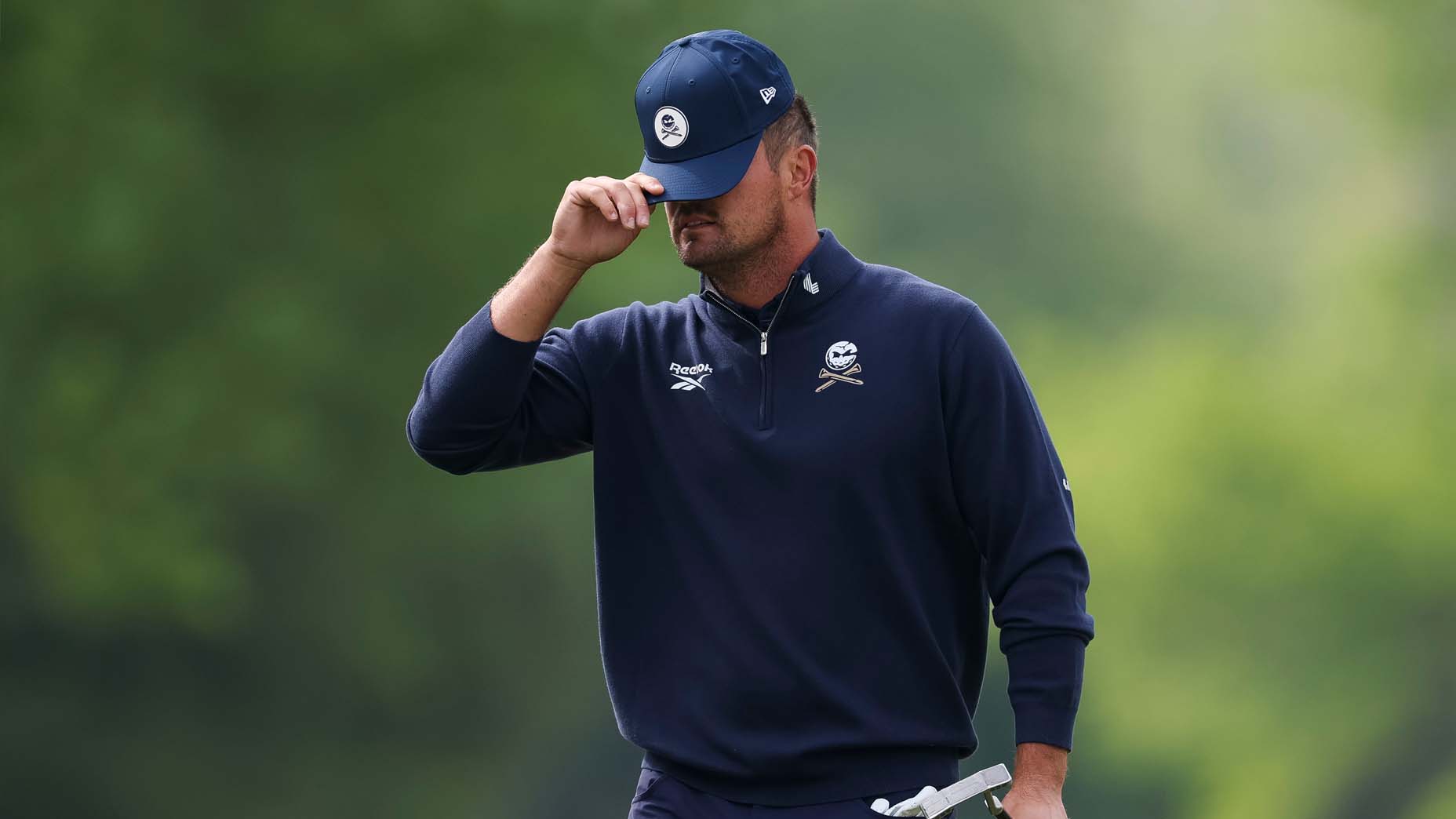 Bryson DeChambeau buries his head in his hat at the PGA Championship
