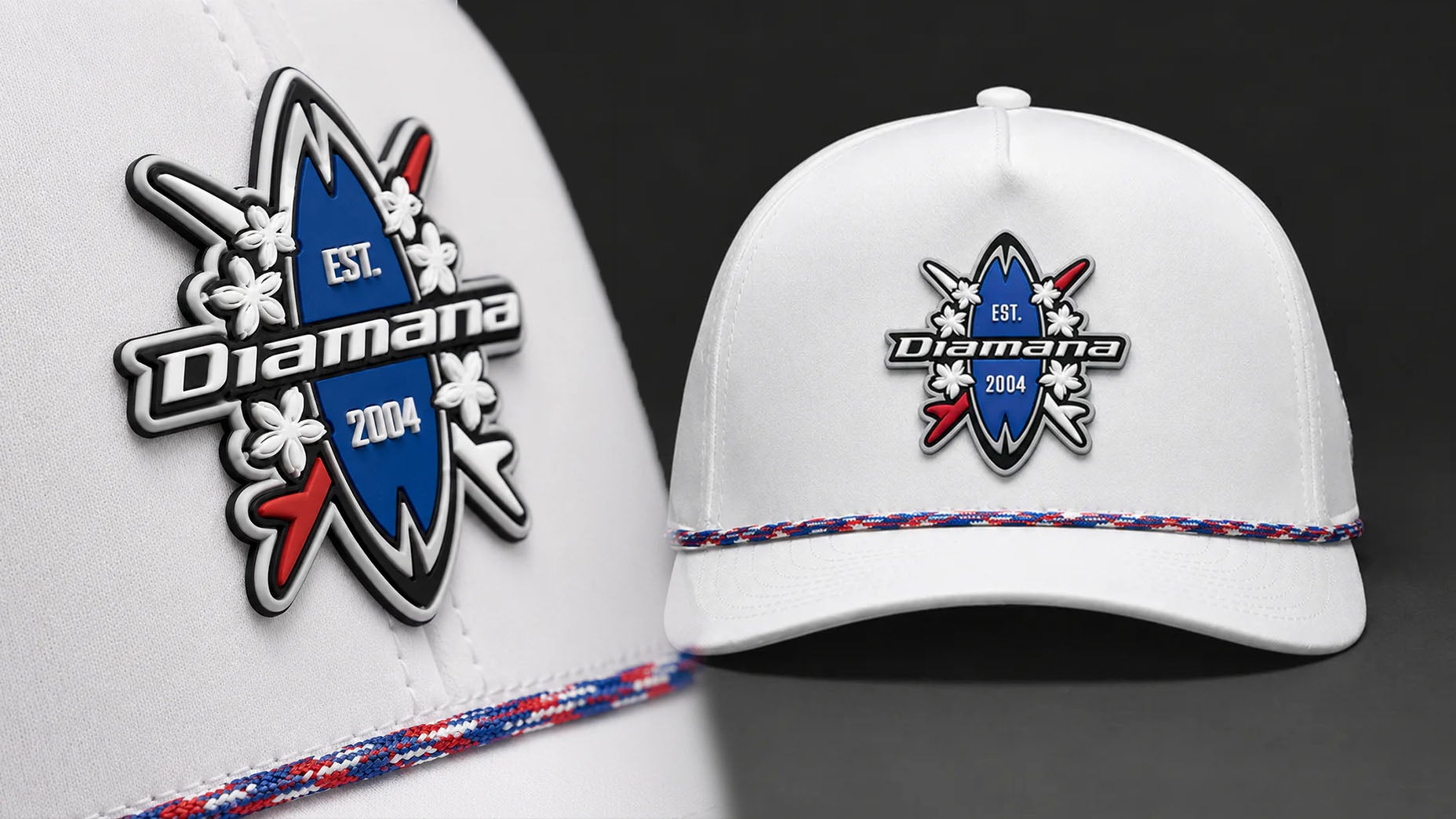 A white cap from the Red White and Blue collection features a blue surfboard-shaped Mitsubishi Diamana logo, EST. 2004, white flowers, and red arrows. A red, white, and blue braided band decorates the brim&mdash;perfect for the US Open.