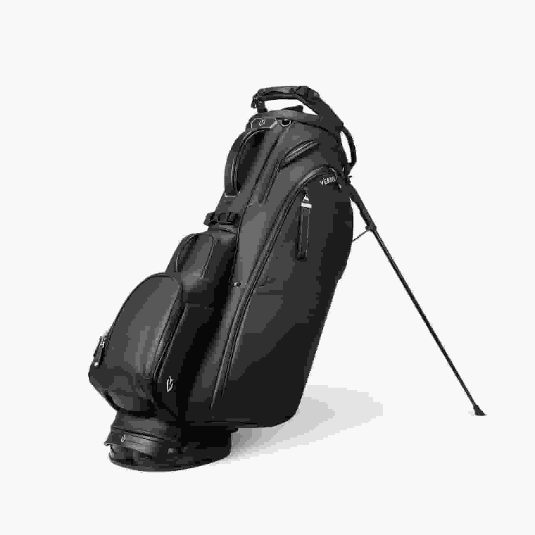 A black golf bag with multiple zippered compartments and a stand, positioned upright on its legs against a white background&mdash;an ideal choice for those seeking the best golf bags 2026 has to offer.