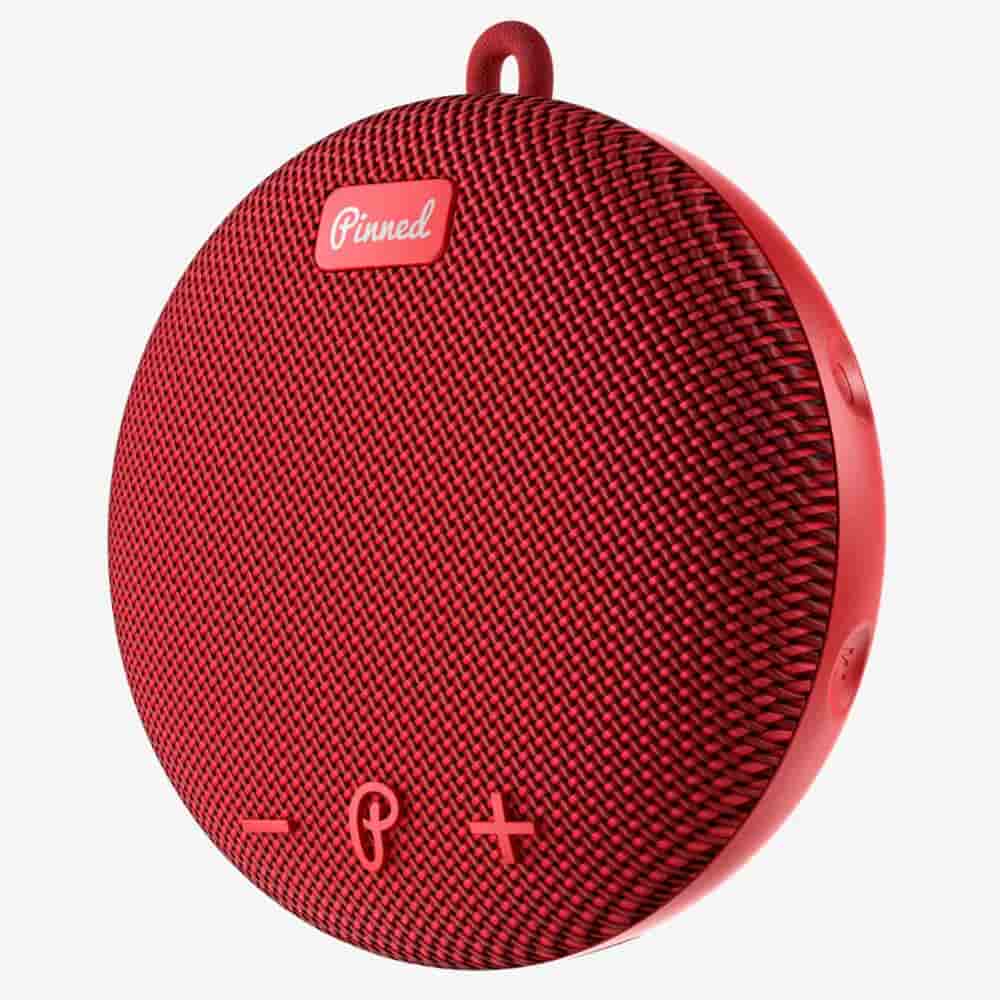 A round, red portable Bluetooth speaker with a fabric front, volume control buttons, and a small loop at the top for hanging&mdash;one of the best deals under $50.