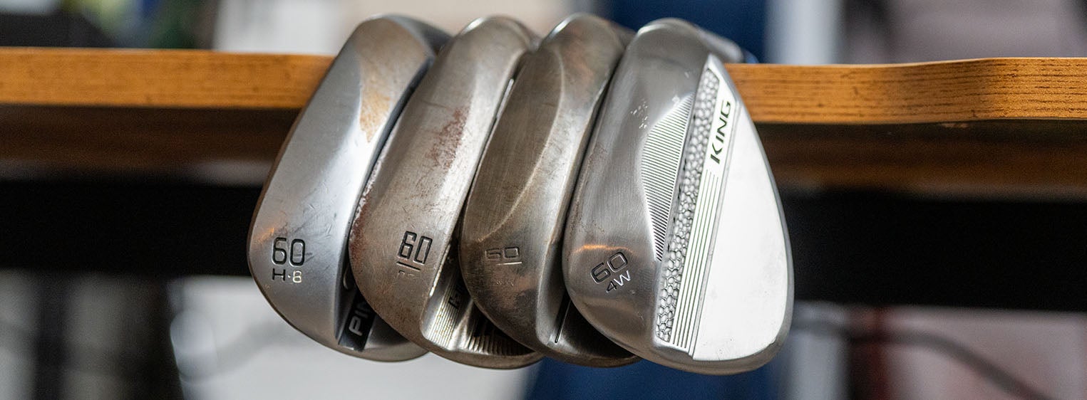 Four perfect wedges sit side by side on the edge of a wooden table, showing their club faces and loft numbers, including two marked 60&mdash;each one Fully Fit 2026 for exceptional precision on the course.