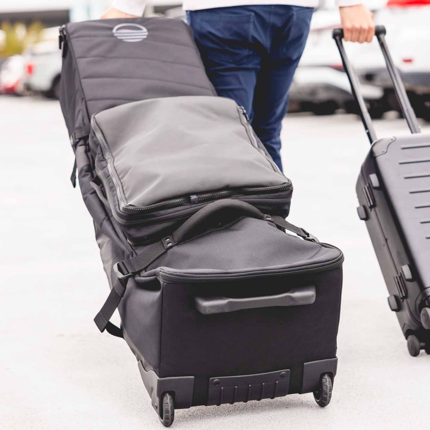 Person pulling a large travel golf bag with wheels in one hand and a hard-shell suitcase in the other, walking outdoors on a paved surface&mdash;this setup is a real game changer for effortless mobility and organization.