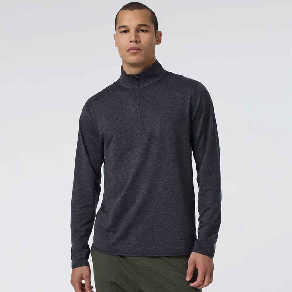 A person wearing a Vuori long-sleeve, dark gray quarter-zip pullover and olive green pants stands against a plain, light background&mdash;perfect golf apparel for Father&rsquo;s Day.