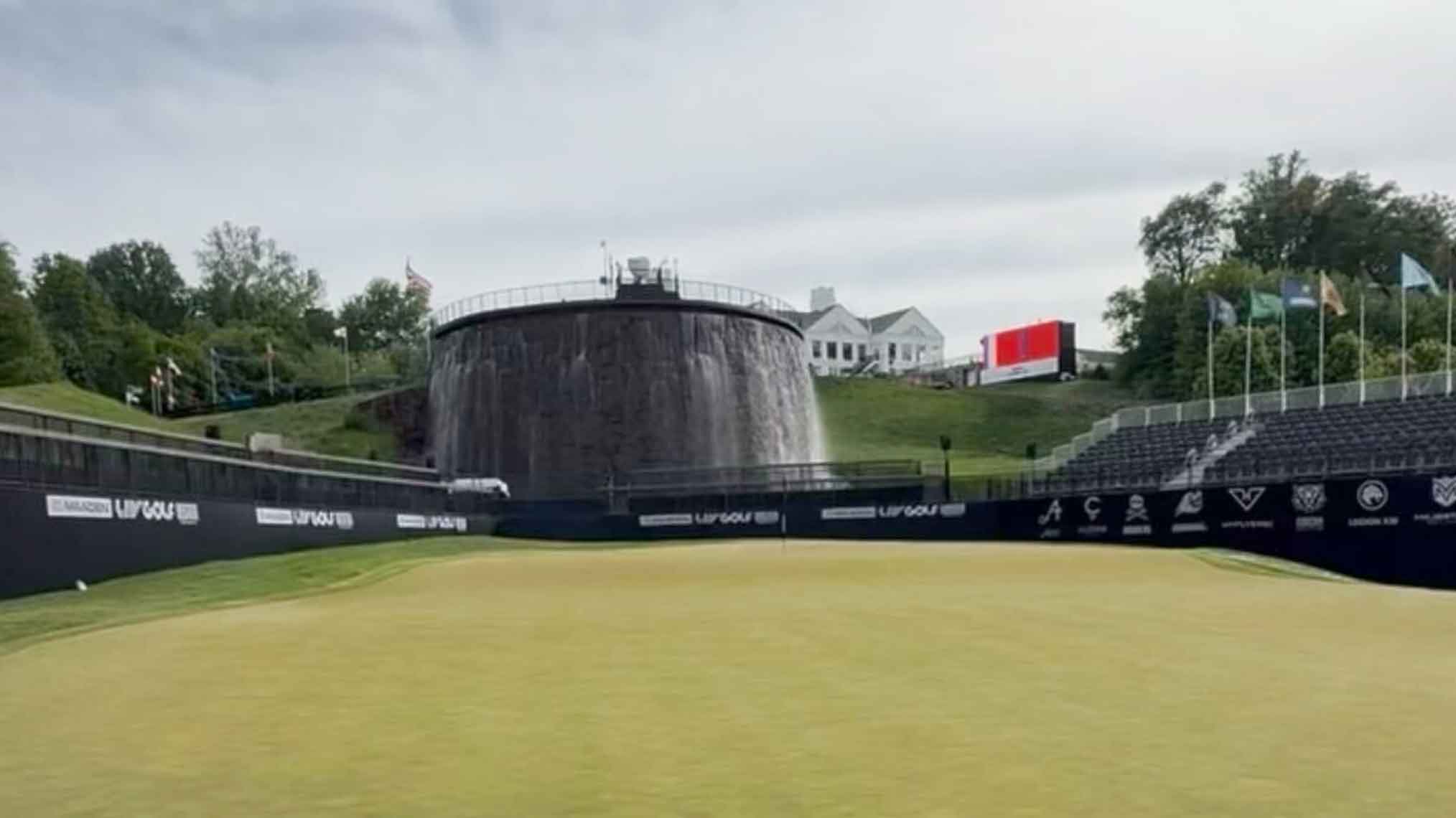A golf green is surrounded by stadium seating, with a round stone structure and a waterfall in the background&mdash;setting the stage for a new era as LIV hosts its first event. Trees, flags, and a large white house sit atop the hill behind the waterfall.