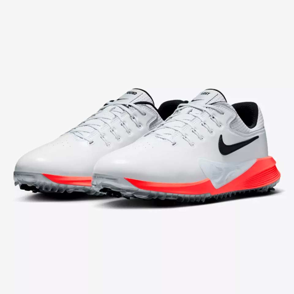 A pair of white Nike golf shoes, inspired by Scottie Scheffler, with black swooshes, black inner lining, and bright red accents on the midsole and outsole, displayed on a plain light background.