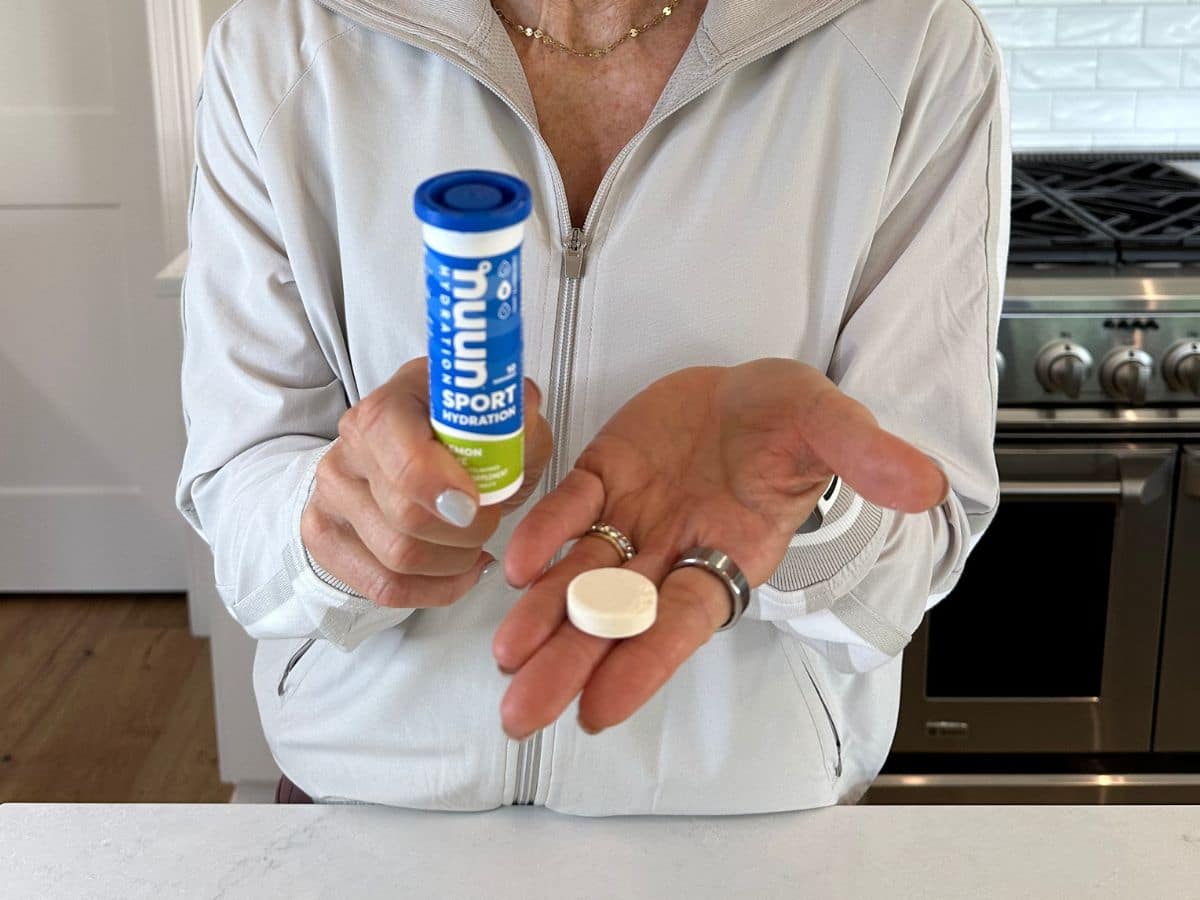 close up of chris freytag holding nuun electrolyte tablets in hand in white kitchen